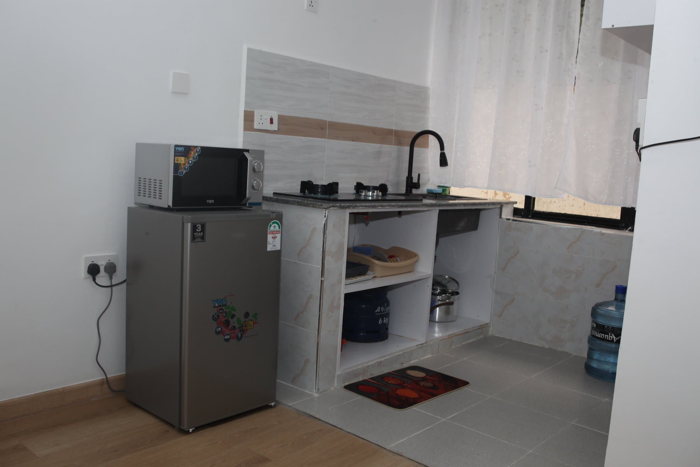 Kitchenette inside a Studio Apartment with gas hob, sink, microwave and fridge